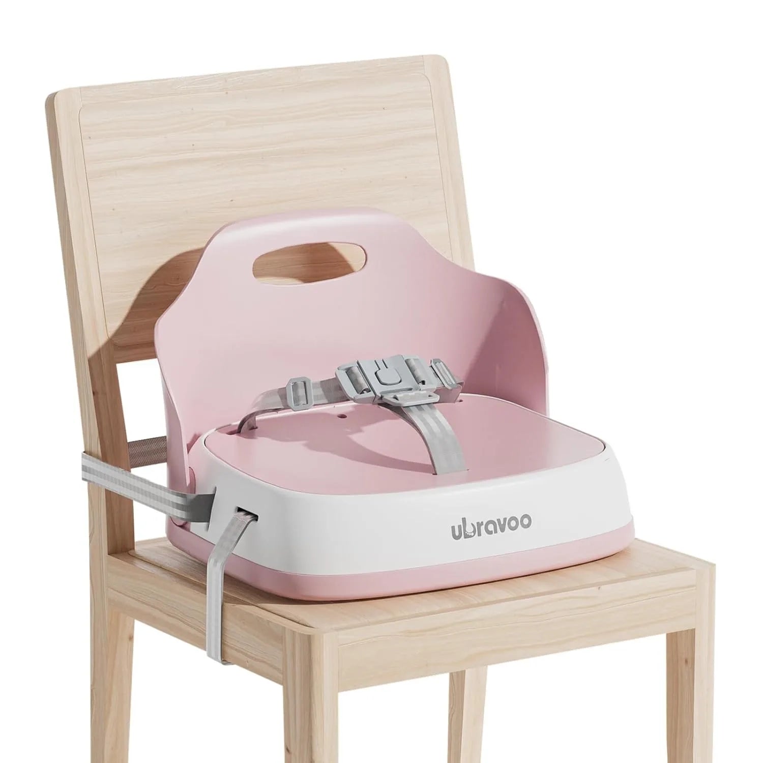Rehausseur de chaise bébé rose sanglé sur une chaise en bois clair